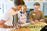 Eine Mutter und ihr Sohn lassen sich im Hotel zu Wanderwegen in der Region beraten.